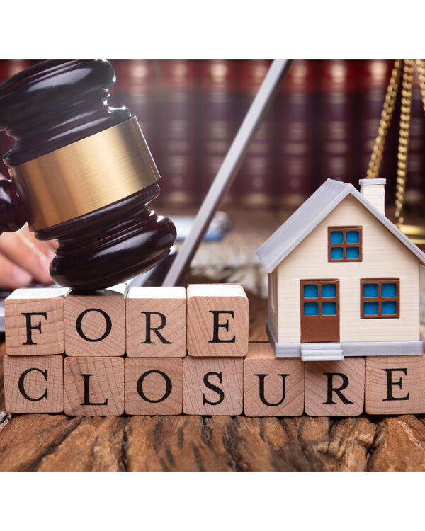 Gavel over blocks with the word foreclosure and a model house
