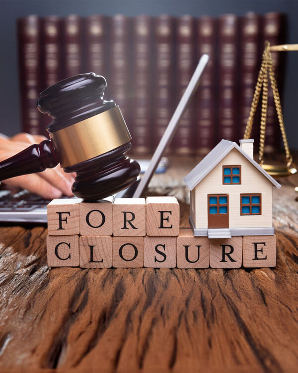 Gavel over blocks with the word foreclosure and a model house
