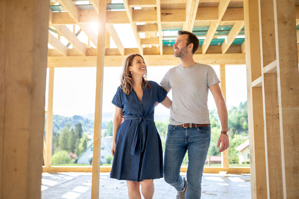Couple walking through frame of home under construction